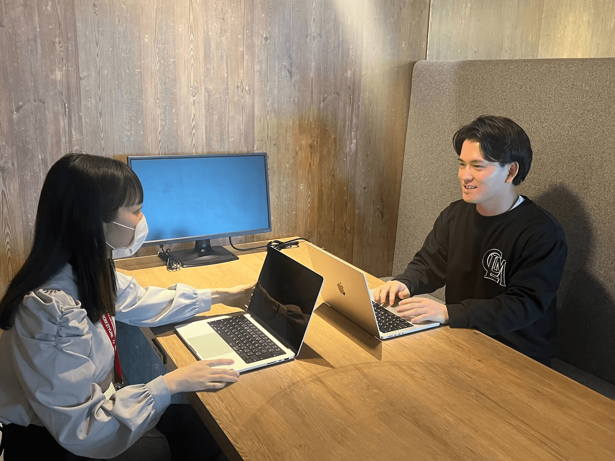 a man and a woman are sitting at a table with laptops