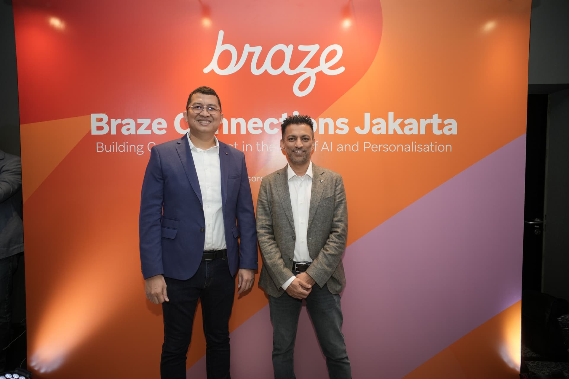 two men in suits are standing next to each other in front of a wall .