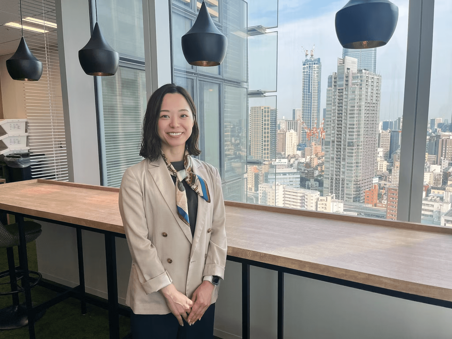 a woman stands in front of a large window overlooking a city