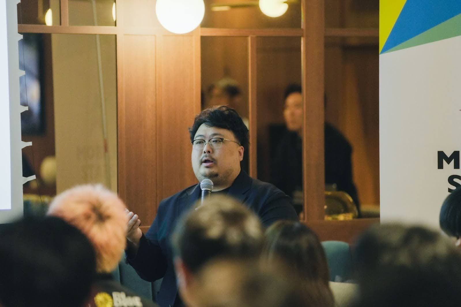 a man is speaking into a microphone in front of a group of people .