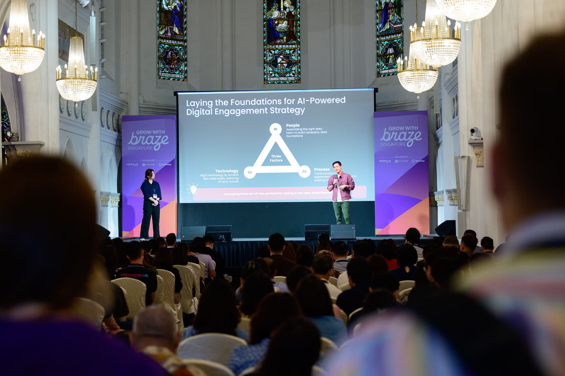 a man is giving a presentation to a large group of people in a venue .